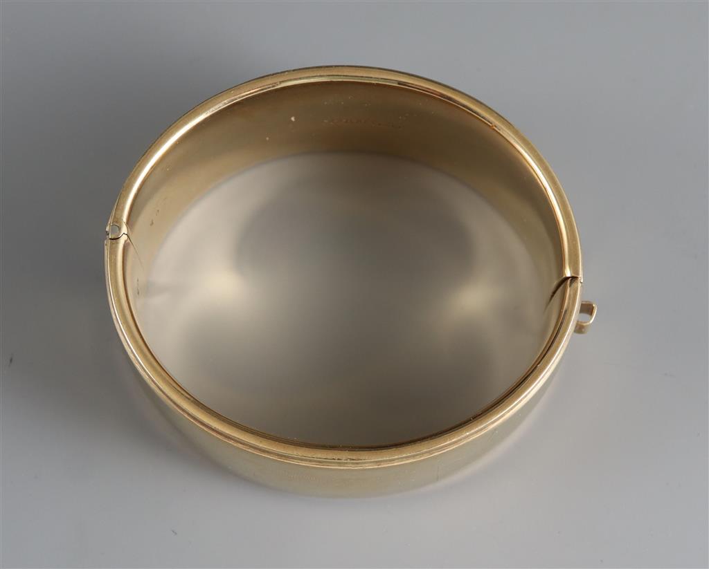 A late 1950s engraved 9ct gold hinged bangle,